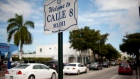Cars pass by a sign welcoming people to Calle 8, or Eighth Street, Miami