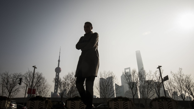 A pedestrian walks along the Bund as buildings in the Lujiazui Financial District stand in the distance in Shanghai, China, on Monday, Feb. 26, 2018. 