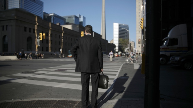 A pedestrian waits to cross a street in the financial district of Toronto, Ontario, Canada, on Wednesday, July 11, 2018. 
