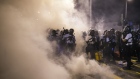 Riot police walk through tear gas as they disperse demonstrators. 