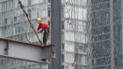 A worker stands on a beam on a construction site in Beijing. 