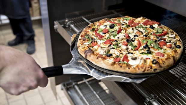 An employee removes a pizza from an oven at a Domino's Pizza Inc. restaurant. 