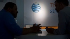 The AT&T Inc. logo is seen past a customer and a retail sales consultant at an AT&T store in Washington, D.C., U.S., on Tuesday, April 21, 2015.