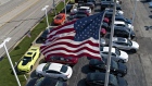 An American flag flies above General Motors Co. vehicles displayed at a car dealership in this aeria
