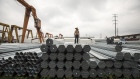 A worker stands on bundles of steel pipe stacked at a stockyard on the outskirts of Shanghai, China, on Thursday, July 5, 2018. U.S. President Donald Trump’s attempts to re-balance global trade have already sent the metals world into a tizzy. As countries respond to U.S. tariffs and sanctions, the disarray is set to increase. Photgrapher: Qilai Shen/Bloomberg 