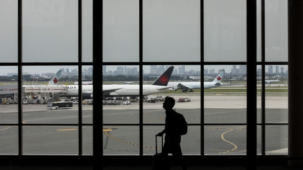 A traveler walks past Air Canada planes at Toronto Pearson International Airport (YYZ) in Toronto, Ontario, Canada, on Monday, July 22, 2019. Air Canada is scheduled to release earnings figures on July 30. Photographer: Brent Lewin/Bloomberg