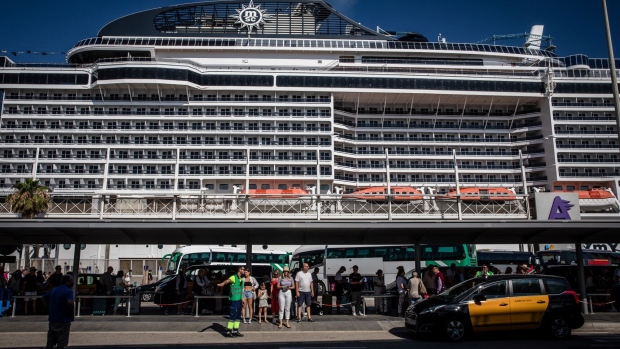 <p>Tourists queue for onward travel at a cruise terminal in Barcelona.</p>