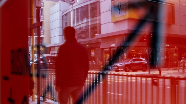 A pedestrian reflected in a sign in Hong Kong, China, on Tuesday, Jan. 23, 2024. Asian stocks advanced, led by Hong Kong, on news that Chinese authorities are considering a rescue package to stem an extended market slump. Photographer: Paul Yeung/Bloomberg