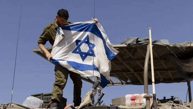An Israeli soldier hangs an Israeli flag on an armored personnel carrier move near the border with the Gaza Strip in Southern Israel on April 15, 2024. Photographer: Amir Levy/Getty Images Europe