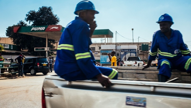 <p>Construction workers ride in the back of a pickup truck past a Puma Energy gas station Lilongwe, Malawi.</p>