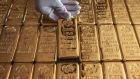 An employee handles one kilogram gold bullions at the YLG Bullion International Co. headquarters in Bangkok, Thailand.