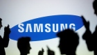 People are silhouetted with mobile devices in front of a screen projected with a Samsung logo