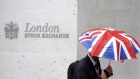 A worker shelters from the rain under a Union Flag umbrella as he passes the London Stock Exchange i