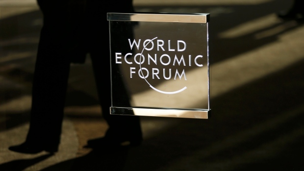 A man walks past the official logo of the World Economic Forum (WEF) in Davos, Switzerland