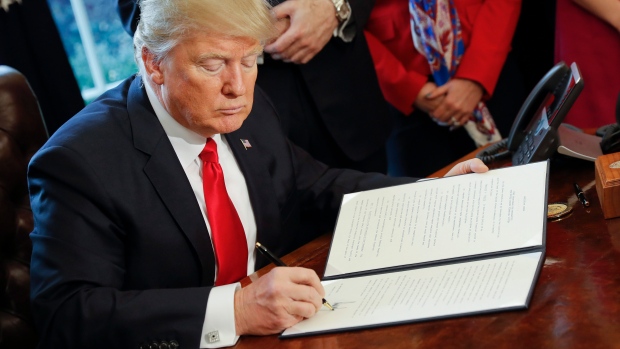 President Donald Trump signs an executive order in the Oval Office of the White House in Washington.