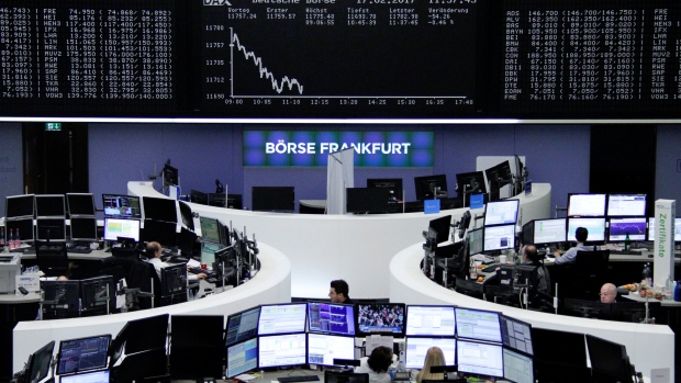 Traders work at their desks in front of the German share price index, DAX board in Frankfurt