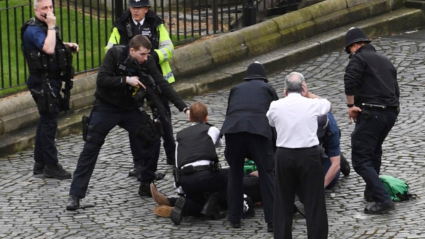 A man treated by emergency services as police look on at the scene outside the Houses of Parliameent