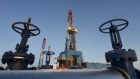 An oil pipe is seen in front of a drilling rig at a Lukoil-owned oil field.