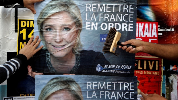 Members of the French National Front political party paste a poster for leader Marine Le Pen. 