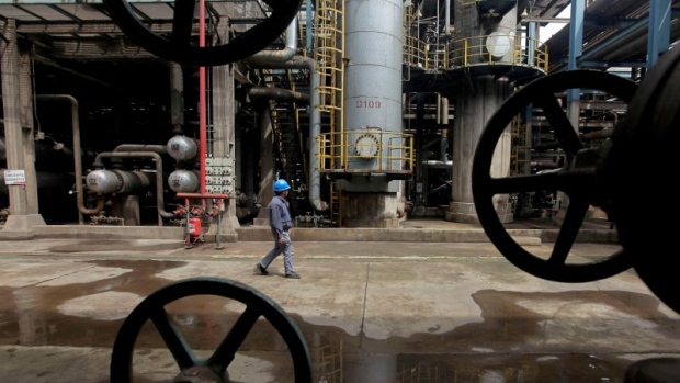 A worker walks past oil pipes at a refinery in Wuhan, Hubei province March 23, 2012. 