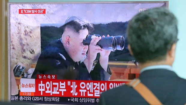 A man walks by a TV screen showing a local news program reporting about North Korea's missile firing