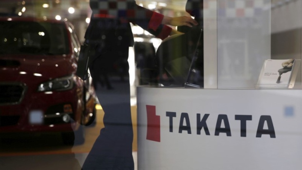 A woman stands next to a logo of Takata Corp at a showroom for vehicles in Tokyo, Japan