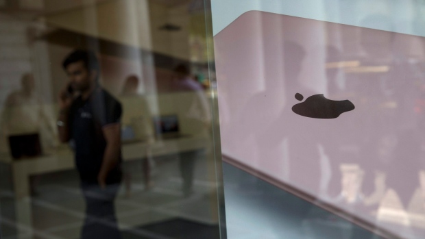 A man speaks on a mobile phone as apple's iPad advertisement is pasted on a store in New Delhi