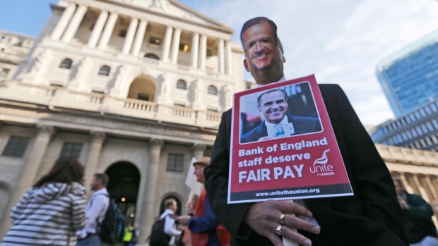 Staff at the Bank of England hold placards and wear masks of Mark Carney