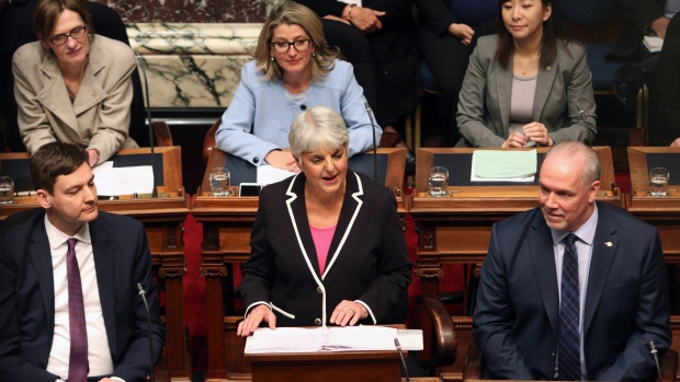 Attorney General David Eby, (left), and Premier John Horgan look on as Finance Minister Carole James