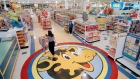 In this July 30, 1996, file photo, a woman pushes a shopping cart over a graphic of Toys R Us masc