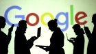 FILE PHOTO: Silhouettes of laptop and mobile device users are seen next to a screen projection of Google logo in this picture illustration