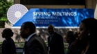 Attendees walk past signage for the International Monetary Fund (IMF) and World Bank spring meetings outside the IMF headquarters in Washington, DC, US, on Monday, April 15, 2024. The IMF and World Bank spring meetings in Washington are expected to draw thousands of delegates, observers and journalists from the fund's 190 member countries. Photographer: Samuel Corum/Bloomberg