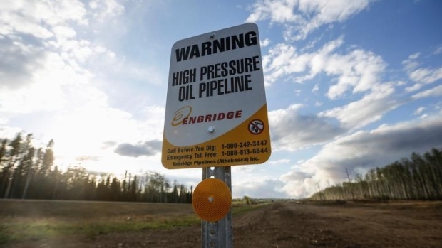 An Enbridge high pressure oil pipeline sign stands as smoke billows from the Fort McMurray