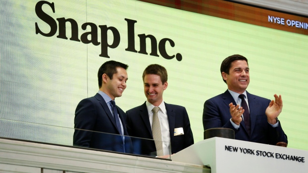 Snap cofounders Evan Spiegel (C) and Bobby Murphy ring the opening bell of the NYSE.