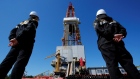 Workers look at a drilling rig of the Rosneft-owned Prirazlomnoye oil field outside Nefteyugansk