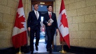Morneau and Trudeau leave the prime minister's office holding copies of the federal budget