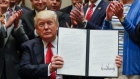 Trump holds up the signed executive order to expand ocean oil drilling