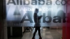 An employee is seen behind a glass wall with the logo of Alibaba at the company's headquarters