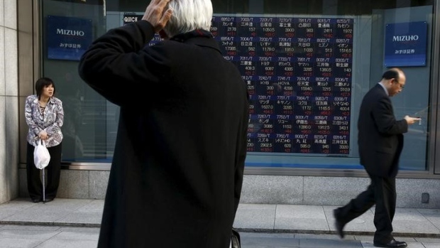 A man looks at an electronic board showing market indices outside a brokerage in Tokyo, Japan 