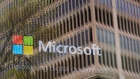 An promotional video plays behind a window reflecting a nearby building at the Microsoft office