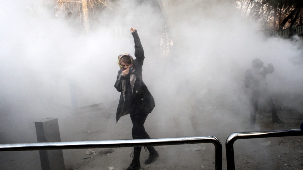 A university student attends a protest inside Tehran University while a smoke grenade is thrown