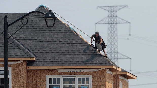 A construction worker shingles the roof of a new home in a development in Ottawa on July 6, 2015. 